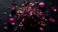 Dried purple rose petals and buds scattered on dark background, creating romantic mood composition for spa, wellness, and aromatherapy designs.