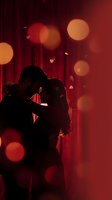 Romantic couple silhouette embracing in warm red lighting with bokeh effects for Valentine's Day and love concepts.