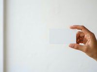 Male hand with medium skin tone holding blank white card against neutral background, suitable for business branding, corporate identity, and marketing mockup designs.