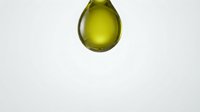 Macro shot of a vibrant yellow-green liquid droplet suspended against a clean white background, showcasing fluid dynamics and surface tension for scientific or cosmetic product design.