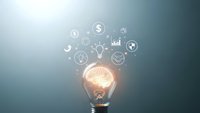 Glowing light bulb with floating business icons representing innovation, finance, and growth concepts for entrepreneurship and creative solutions.