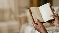 Open book with blank pages held by hands of mature person with brown skin tone, suitable for education, literature, reading, writing, journaling, and publishing projects.