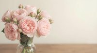 Soft pink roses in glass vase on wooden table against neutral background. Romantic floral arrangement for home decor, wedding celebration, gift concept.