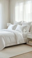 Serene bedroom with white linens, pillows, and sheer curtains filtering natural light through tall windows, ideal for home decor and lifestyle content.