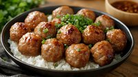 Juicy glazed meatballs served on white rice with fresh herbs garnish and dipping sauce, close up view of Asian cuisine on dark plate.