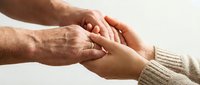 Elderly hands gently holding young hands, symbolizing care, support, and intergenerational connection between family members on light background.