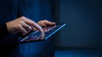 Professional businessman using digital tablet with glowing screen in dark office environment for modern technology and business communication applications.