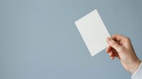 Hand holding blank white card or paper against blue background, suitable for business presentations, marketing mockups, and promotional designs.