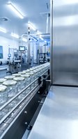 Modern pharmaceutical manufacturing facility with sterile production line conveyor belt transporting glass vials in clean room environment for medicine packaging.