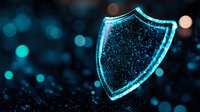 Glowing blue shield icon on dark background with bokeh effect and particles, representing digital security and cyber protection concept.