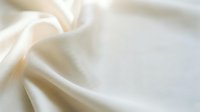 Soft cream silk fabric with elegant flowing folds and luxurious texture for fashion design, wedding decor, and premium textile backgrounds.