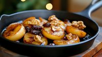 Caramelized plums with walnuts in cast iron skillet, golden brown fruit dessert with nuts, rustic cooking presentation for culinary blogs.