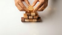 Male hands placing wooden block with dollar sign on top of stacked wooden cubes, representing financial growth, investment strategy, and business success on white background.