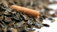 Dried black tea leaves with cinnamon stick macro shot showing texture and detail of loose leaf tea. Natural organic beverage ingredients on white background.
