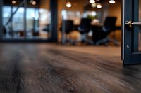 Close-up view of dark wooden floor in modern office space with blurred background showing chairs and windows, low angle perspective for business interior design.