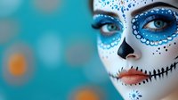 Young woman with traditional Day of the Dead sugar skull face paint featuring intricate blue and white designs, decorative dots and floral patterns on turquoise background.