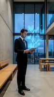 Professional businessman using tablet with holographic financial data charts and graphs in modern office building at night.