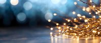 Glowing warm fairy lights creating magical bokeh effect against dark blue background, festive winter holiday atmosphere with golden illumination.
