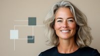Confident mature Caucasian woman with silver gray hair and natural smile wearing black top against beige wall with geometric decoration, looking at camera.
