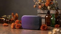 Purple wireless speaker surrounded by autumn orange chrysanthemum flowers and vintage glass bottles on wooden surface for home decor and music lifestyle.