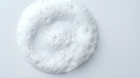 White foam cleanser circle on light background, top view. Soap lather texture for skincare, beauty, and cosmetic product presentations.