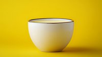 White ceramic bowl with black rim on vibrant yellow background, minimalist composition with soft shadow creates modern, clean aesthetic for food photography.