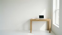 Minimalist wooden desk with laptop in bright modern office space with white walls and natural window light for remote work and productivity.