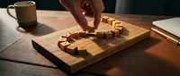Hand placing wooden puzzle piece to complete word LOVE on cutting board with warm morning light and coffee cup creating cozy romantic atmosphere.