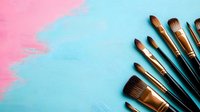 Professional makeup brushes arranged in diagonal composition on pink and blue pastel background with copy space for beauty and cosmetics marketing.