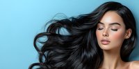 Young Asian woman with flowing black hair and natural makeup against blue background, eyes closed in serene expression. Professional beauty portrait.