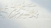 Elegant embossed lily flowers carved in white plaster wall creating sophisticated textural relief pattern for luxury interior design and decoration.