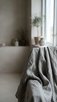 Soft gray linen fabric draped naturally in minimalist bathroom interior with bathtub and plants creating serene spa atmosphere for home decor and wellness.