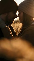 Intimate couple sharing tender moment in golden sunset light wearing winter hats, romantic connection and love concept for relationship content.