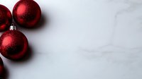 Red Christmas ornaments on white marble background with copy space for holiday greeting cards and festive decorations.