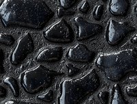 Wet black stones with water drops on dark textured surface create dramatic contrast and shine, capturing natural zen atmosphere for spa and wellness designs.