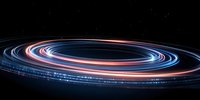 Glowing spiral light trails in blue and orange colors against dark background create dynamic motion effect with long exposure technique. Abstract space concept.