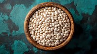 Raw white navy beans in wooden bowl on turquoise rustic background. Traditional legumes for healthy protein-rich cooking and vegetarian cuisine.