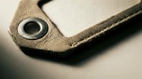 Brown leather material corner with metal eyelet grommet showing detailed stitching and texture for crafting and manufacturing projects.