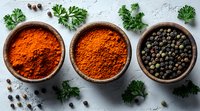 Ground paprika powder and black peppercorns in rustic ceramic bowls decorated with fresh parsley leaves on light stone background. Food seasoning concept.