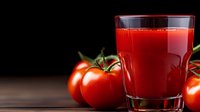 Fresh tomato juice in glass with ripe red tomatoes on wooden surface against dark background, healthy natural vegetable drink for detox and wellness.