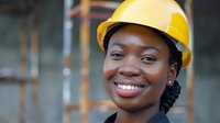 Professional African American female construction worker or engineer wearing yellow hard hat smiling confidently at construction site, perfect for diversity and inclusion campaigns.
