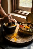 Traditional spice grinding with mortar and pestle in rustic kitchen setting with colorful spices in wooden containers for authentic cooking preparation.
