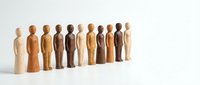 Wooden figurines in various skin tones standing in a row, representing diversity, inclusion, teamwork, and community unity for business and social concepts.
