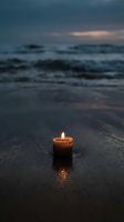 Burning candle on wet beach sand at twilight with ocean waves and dramatic cloudy sky creating peaceful meditation atmosphere for spiritual wellness concepts.