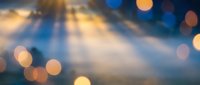 Dreamy bokeh background with golden light rays streaming through darkness creating magical atmosphere for presentations and design projects.