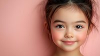 Young Asian girl with rosy cheeks smiling warmly against soft pink background for children portraits and family photography projects.