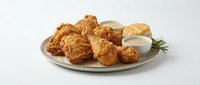 Crispy fried chicken pieces served on a plate with creamy dipping sauce and fresh rosemary garnish, ready for restaurant menus and food service marketing.