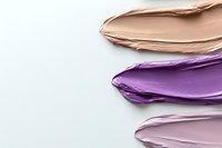 Colorful makeup foundation smears in nude, purple and pink tones on white background. Cosmetic texture swatches for beauty and skincare products.