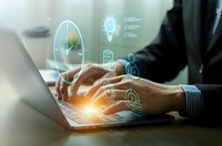 Businessman hands typing on laptop with glowing digital innovation icons floating above keyboard representing technology solutions and creative ideas.