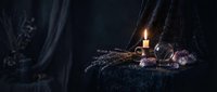 Dark mystical still life with burning candle, dried lavender, crystals and vintage elements creating atmospheric witchcraft scene for spiritual design projects.